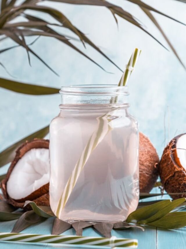 Coconut water and coconuts on a bright pastel background, selective focus.