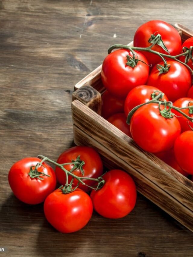 Fresh tomatoes in a box. On a wooden table.