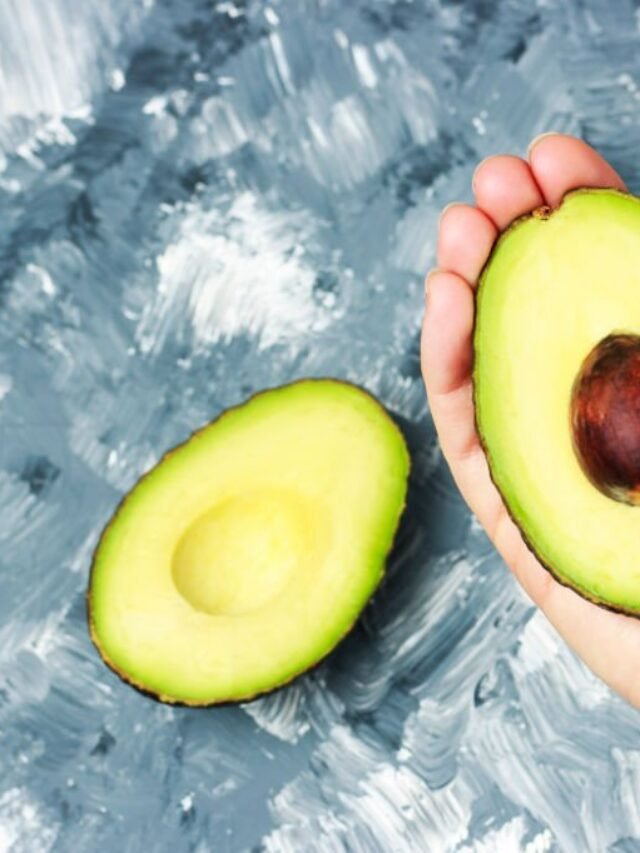 Fresh cut avocado in female hand close-up, top view